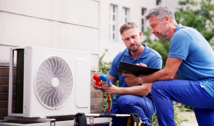 HVAC technicians reviewing an outdoor air conditioning unit in Littleton, CO