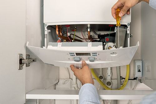 HVAC technician repairing an indoor boiler in Littleton