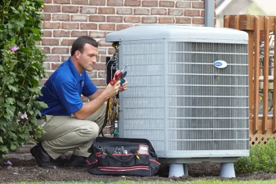 HVAC technician inspecting an outdoor air conditioning unit in Littleton, CO
