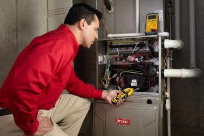 Heating and air conditioning technician servicing an indoor furnace in Littleton, CO